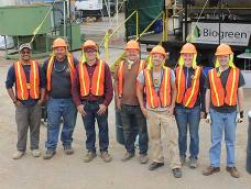 A group of researchers and students in industrial safety clothing in front of a large torrefier